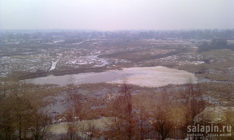 15 апреля, ледовая обстановка в верховьях Пехорки. Где есть течение, лед подтачивает, на льду в заливе без течения сидят рыболовы.